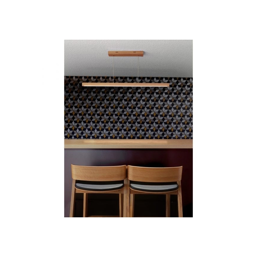 Drevené svietidlo visí nad barovým pultom. Svietidlo svieti nad dvoma drevenými barovými stoličkami s tmavými sedákmi. Za pultom je stena s geometrickým vzorom dlaždíc v odtieňoch šedej, čiernej a zlatej.