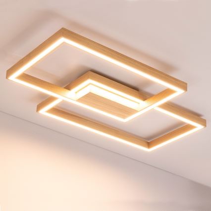 Drevené stropné svietidlo s LED osvetlením je pripevnené k stropu. Svetlo svieti. Svietidlo je zložené z prepletených obdĺžnikových drevených rámov.