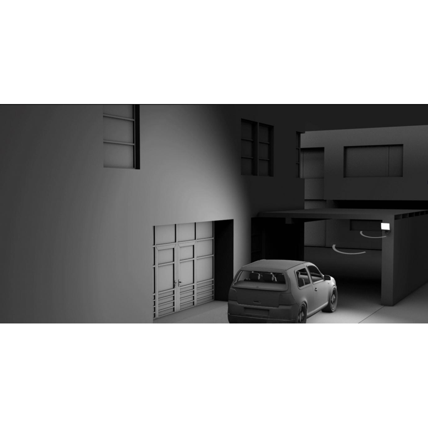 Auto stojí pred garážou. V pozadí je moderná budova. Svetlo svieti z exteriéru.