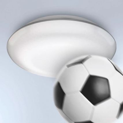 Biela guľatá lampa s tenkým strieborným okrajom je zasiahnutá futbalovou loptou. Lampa je pripevnená k stropu.
