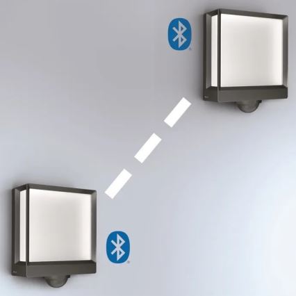 Dve nástenné svietidlá s plochým bielym difúzorom komunikujú bezdrôtovo prostredníctvom Bluetooth. Svietidlá sú namontované na svetlej stene. Prebieha bezdrôtový prenos dát.
