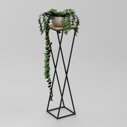Kvetináč s popínavou rastlinou stojí na vysokom kovovom stojane s drevenou podložkou. Stojan má X-tvarovanú konštrukciu. Rastlina previsá zo stojana.