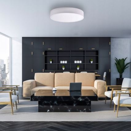 Svietidlo svieti v modernom interiéri. Pohovka sa nachádza pred konferenčným stolíkom z tmavého mramoru. V pozadí je tmavá knižnica s policami.