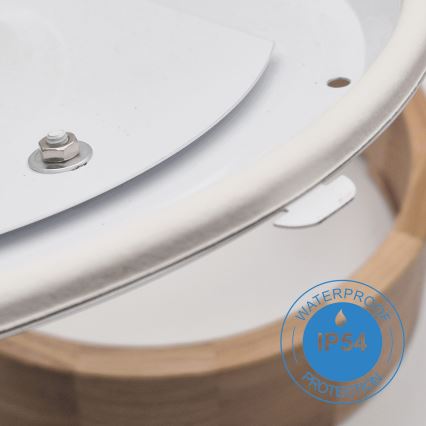 Biela krycia časť s upevňovacím skrutkovým spojom sa čiastočne odklápa od dreveného podkladu. Na dreve je označenie: „WATERPROOF IP54 PROTECTION“.