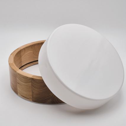 Drevená nádoba s okrúhlym bielym viečkom je otvorená. Nádoba je z svetlého dreva, viečko je hladké a biele. Nachádza sa na bielom pozadí.