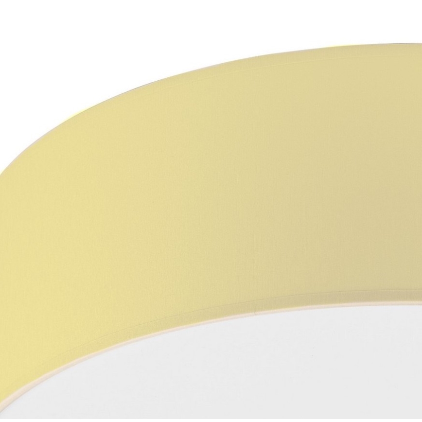 Svetlo s bledžltým tienidlom v tvare mierne prehnutého disku je zobrazené zblízka. Tienidlo je z látky. Pozornosť sa sústreďuje na textúru a farbu tienidla.