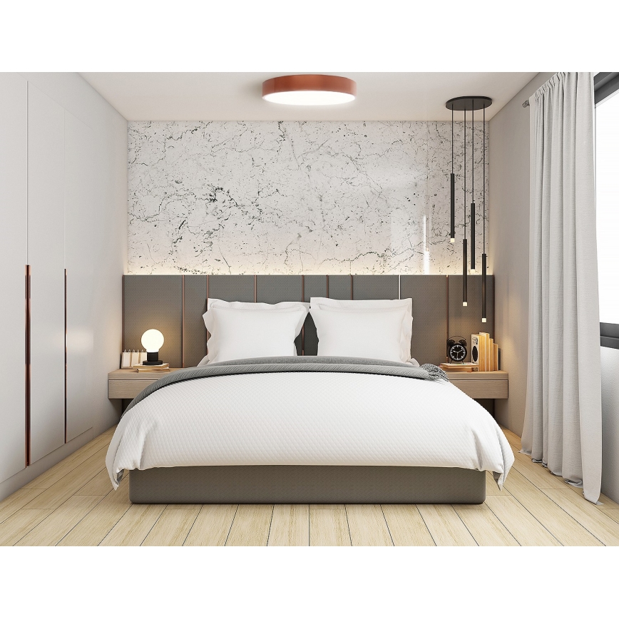 Dvojposteľ je upravená s posteľnou bielizňou v sivej a bielej farbe. Nachádza sa v spálni s mramorovým obkladom a dvoma nočnými stolíkmi. Nad posteľou visí moderné stropné svietidlo a v rohu miestnosti visí luster s viacerými svetlami.