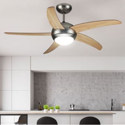 Stropný ventilátor s drevenými lopatkami a zabudovaným svetlom sa otáča v modernej kuchyni s betónovou stenou a kuchynskou linkou.