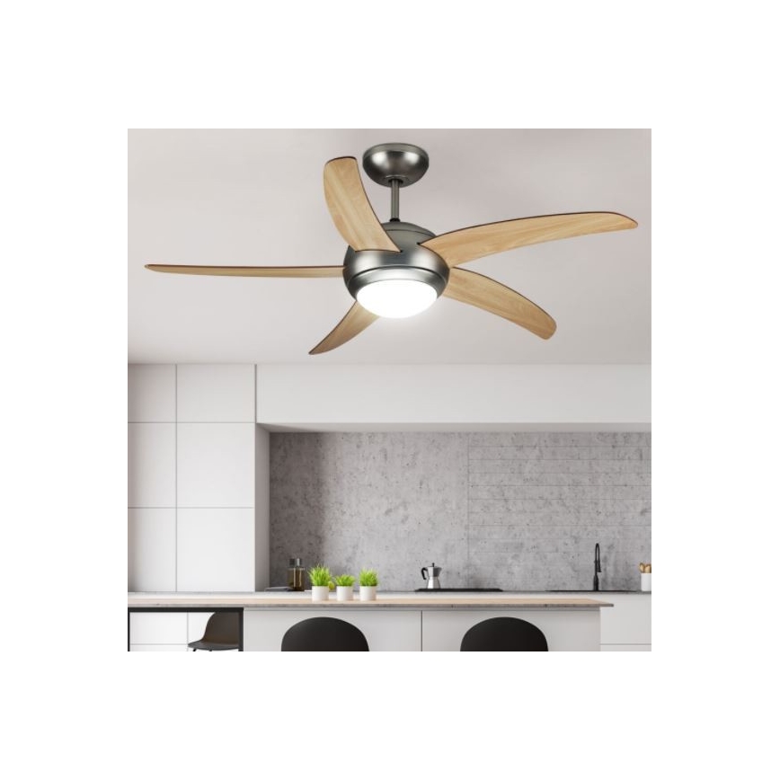 Stropný ventilátor s drevenými lopatkami a zabudovaným svetlom sa otáča v modernej kuchyni s betónovou stenou a kuchynskou linkou.