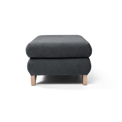 Čalúnená podnožka tmavosivej farby stojí na svetlohnedých drevených nožičkách. Je umiestnená na bielom pozadí.