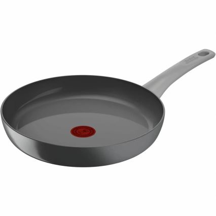 Šedá panvica s dlhou svetlošedou rúčkou leží na bielom pozadí. Na dne panvice je červený kruhový symbol.