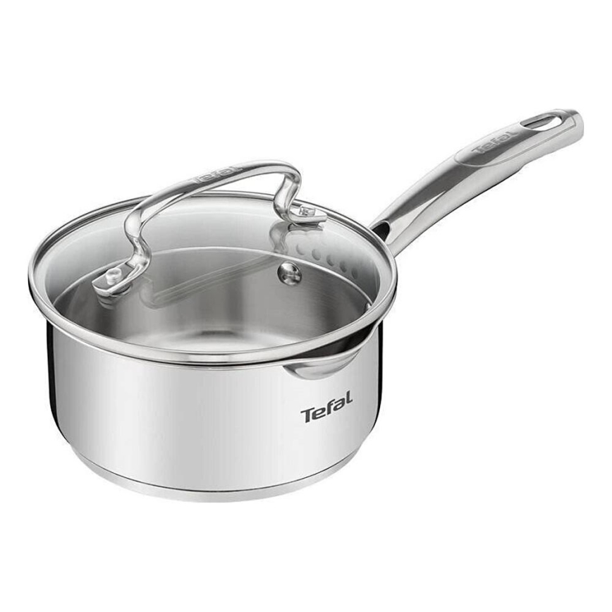 Nerezový hrniec Tefal s priehľadným skleneným vekom je pripravený na varenie. Má ergonomickú rukoväť a logo Tefal je viditeľné na boku. Nachádza sa na bielom pozadí.