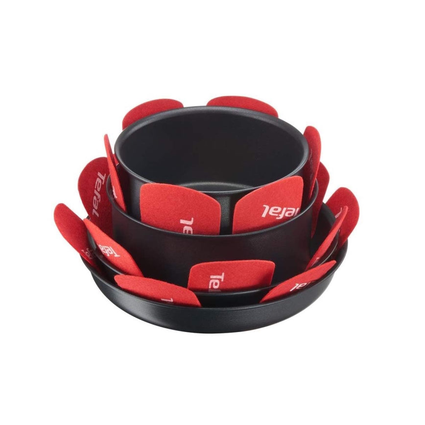 Súprava troch čiernych panvíc Tefal je poskladaná na seba. Medzi jednotlivými panvicami sú červené ochranné podložky s logom Tefal. Panvice sú na bielom pozadí.