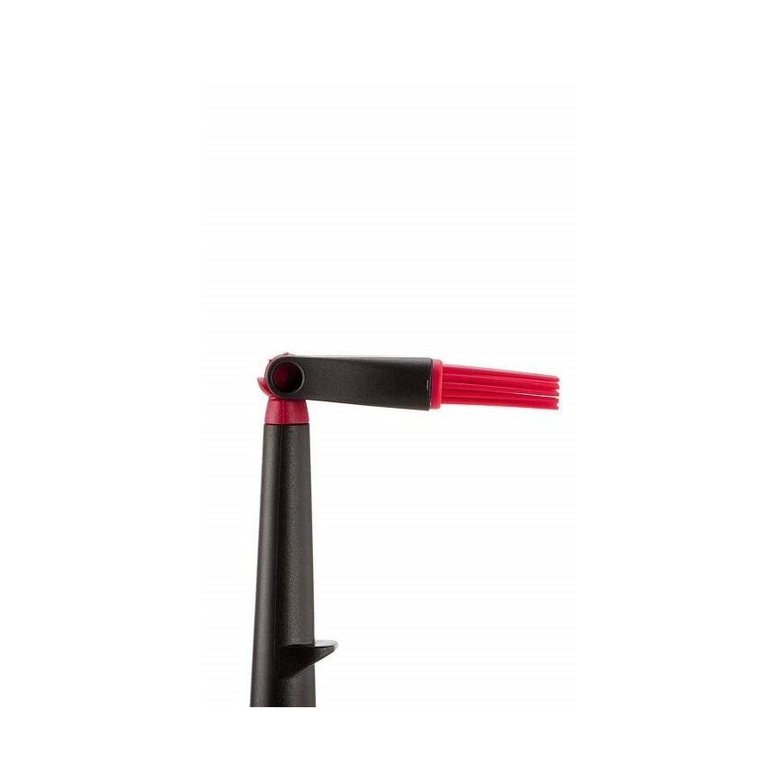 Čierna rukoväť s červenou silikónovou kefkou je otočená do uhla. Kefka má krátku rúčku a dlhé, tenké červené štetinky. Rukoväť má na spodku malý výčnelok. Pozadí je biele.