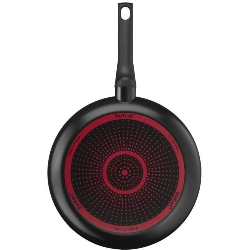 Panvica Tefal s čiernym povrchom a červeným dnom s bodkovaným vzorom je zobrazená zhora. Na dne je nápis Tefal a Made in France.