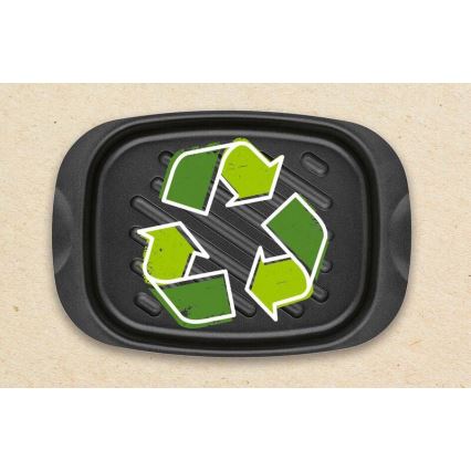 Čierny grilovací plech s reliéfnymi drážkami zobrazuje zelenú recyklačnú značku. Plech je umiestnený na svetlohnedom papierovom podklade.