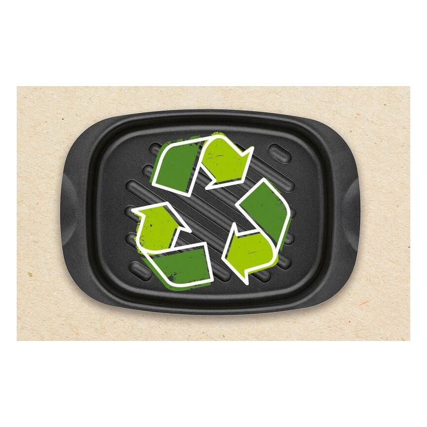 Čierny grilovací plech s reliéfnymi drážkami zobrazuje zelenú recyklačnú značku. Plech je umiestnený na svetlohnedom papierovom podklade.