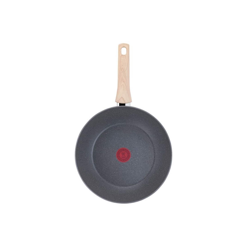 Wok s drevenou rúčkou a sivou nepriľnavou povrchovou úpravou je zobrazený zhora. Na dne je malé červené logo. Wok je umiestnený na bielom pozadí.