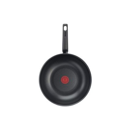 Čierna wok panvica s čiernou rukoväťou Tefal je zobrazená zhora. Panvica má na dne červený kruhový symbol. Pozadí je biele.