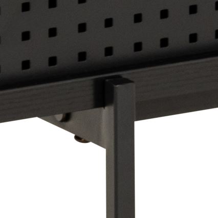 Čierna kovová polica s perforovanou prednou stranou je pripevnená k čiernym kovovým nohám skrutkami. Konštrukcia je jednoduchá a minimalistická.