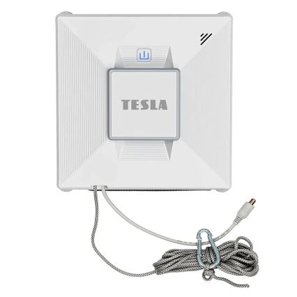 Automatický čistič okien Tesla čistí okná. Je biely, štvorcového tvaru, s pripojenou šnúrou a karabínkou. Na čističi je nápis „TESLA“.