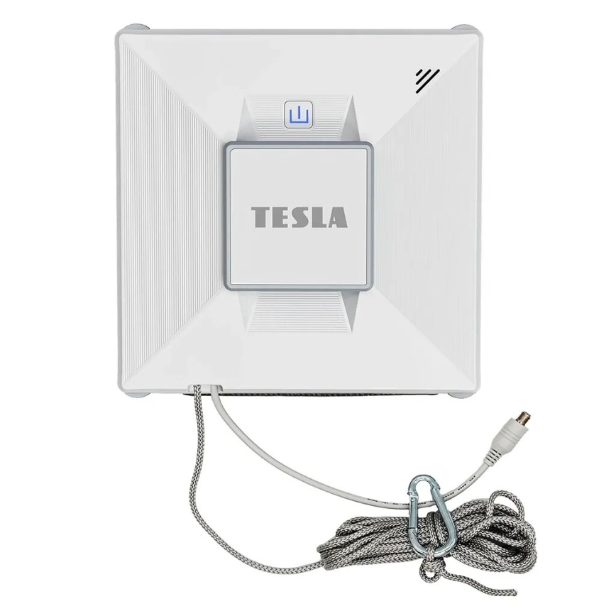Automatický čistič okien Tesla čistí okná. Je biely, štvorcového tvaru, s pripojenou šnúrou a karabínkou. Na čističi je nápis „TESLA“.