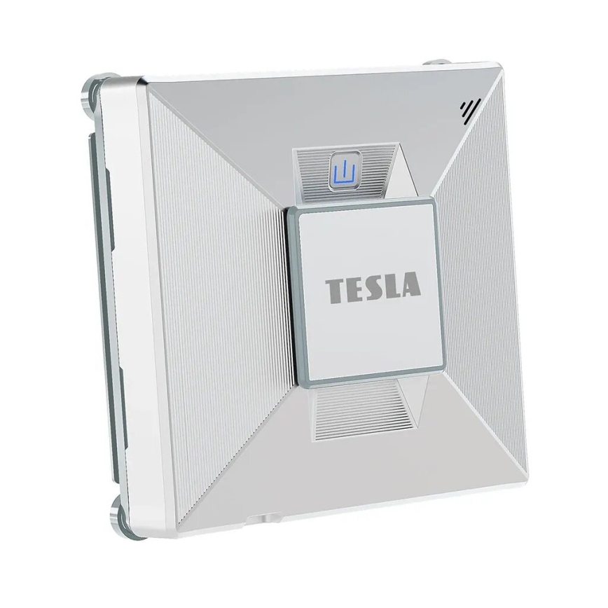Automatický čistič okien Tesla je zobrazený na bielom pozadí. Zariadenie je strieborné, štvorcového tvaru s výrazným označením „TESLA“. Má integrované tlačidlo s ikonou kvapiek vody.