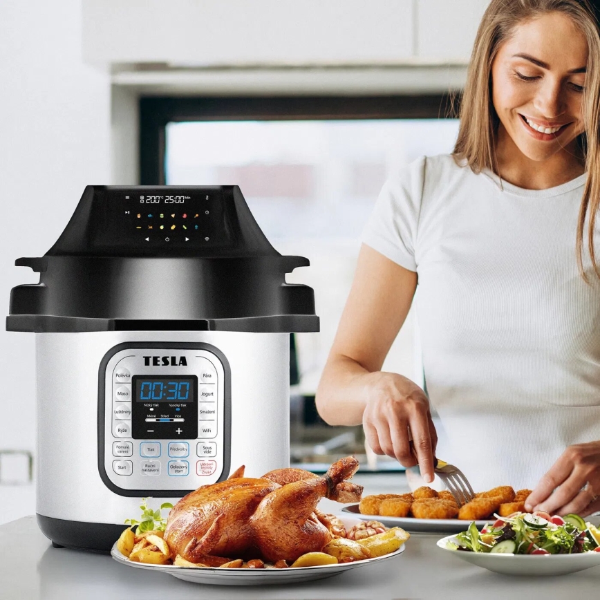 Multifunkčný tlakový hrniec Tesla s displejom zobrazujúcim „00:30“ pripravuje jedlo. Na stole je pečené kura s prílohami, žena pri stole servíruje jedlo.