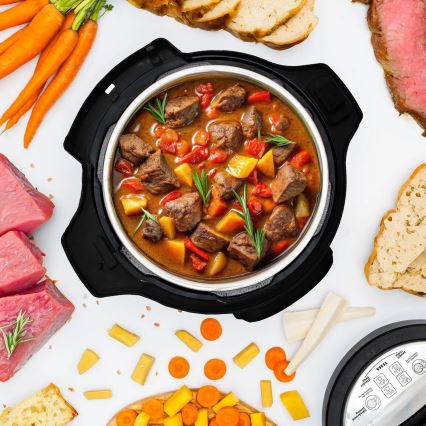 Tlakáč pripravuje mäsový guláš. Guláš obsahuje hovädzie mäso, zeleninu a bylinky. Okrem tlakáča sú na obrázku suroviny ako mrkva, zemiaky, chlieb a surové mäso.