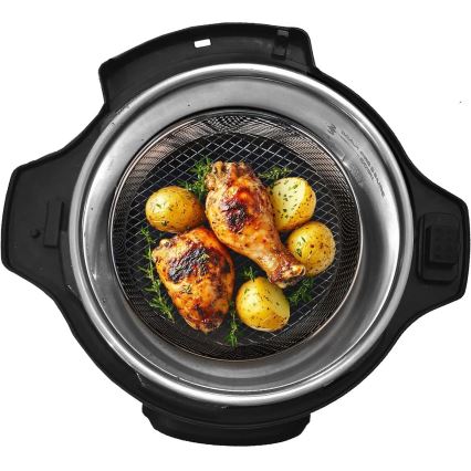 Dve kuracie stehná a niekoľko zemiakov sa pripravujú v kovovej košíkovej vložke vnútri tlakového hrnca s čiernym vonkajším telom.