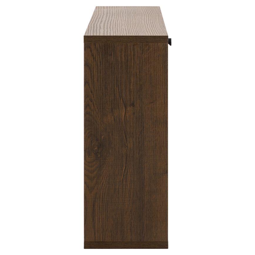 Tmavohnedá úzka skriňa stojí na bielom pozadí. Je zobrazená z boku, vidno jej bočnú stenu a vrchnú dosku. Na pravej strane je malé čierne úchytky.