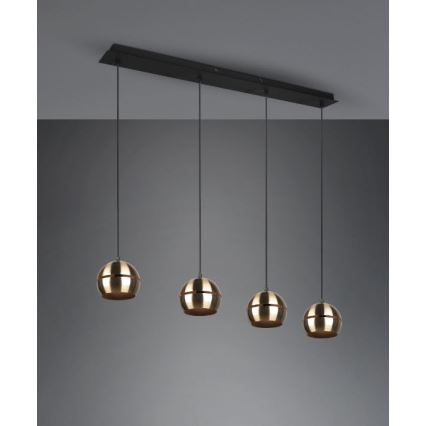 Štvorramenné závesné svietidlo visí zo stropnej lišty. Štyri zlaté guľové tienidlá sú zavesené na čiernych kábloch. Lišta je čierna a pripevnená k stropu.