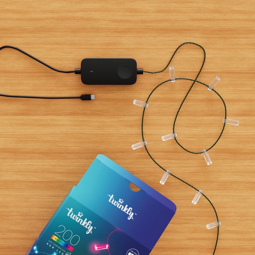 LED svetielka s čiernym USB adaptérom sú pripojené na drevenom povrchu. Svietidlá sú usporiadané do tvaru slučky. Balenie zobrazuje názov „twinkly“ a počet „200“ multifarebných RGB LED.