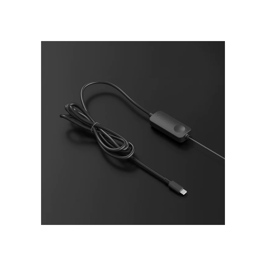 Čierny kábel s USB-C konektorom je pripojený k malej čiernej krabičke s tlačidlom. Krabica je umiestnená na tmavosivej ploche.