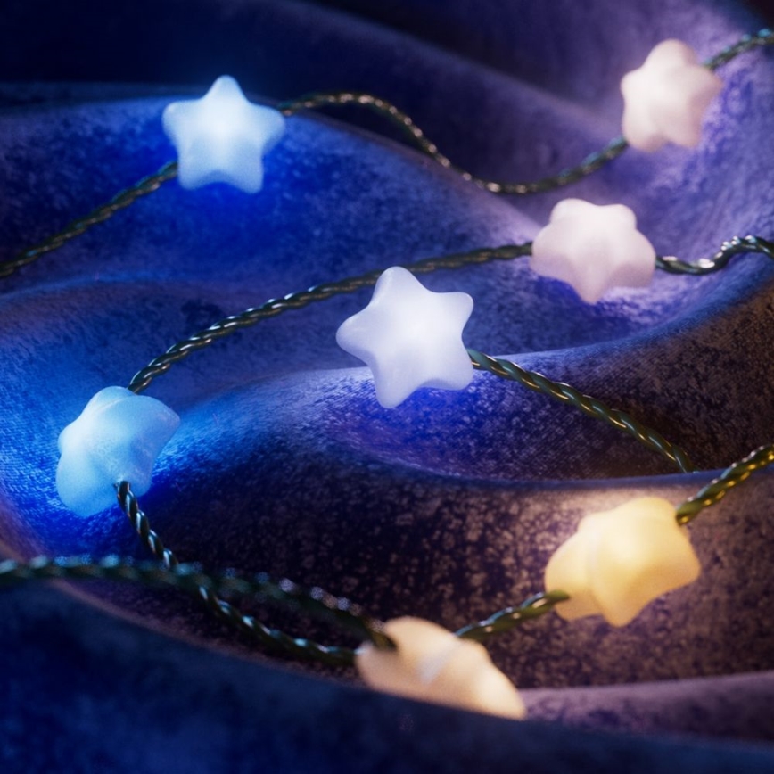 Svetielkujúce hviezdy tvarované LED diódy sú navlečené na tenkom drôte. Viacfarebné svetlá sú rozložené po tmavom, zvlnenom povrchu.