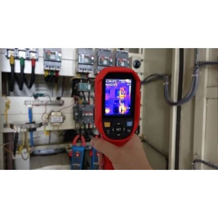 Termokamera meria teplotu elektrického rozvádzača. Na displeji sa zobrazujú teploty 34,0°C a 63,9°C. Kontext tvorí rozvádzač s káblami a ďalším elektrickým zariadením.