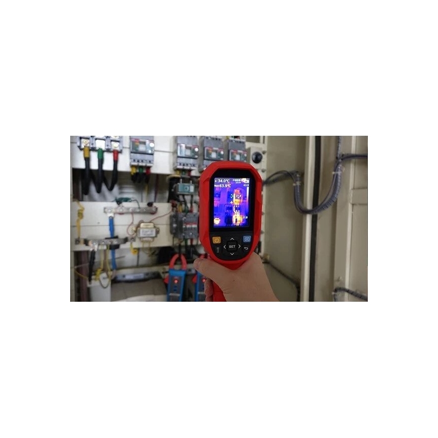 Termokamera meria teplotu elektrického rozvádzača. Na displeji sa zobrazujú teploty 34,0°C a 63,9°C. Kontext tvorí rozvádzač s káblami a ďalším elektrickým zariadením.