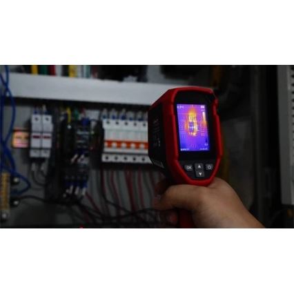 Termokamera sníma teplotu elektrického rozvádzača. Zariadenie drží ruka. Na displeji termokamery je zobrazený tepelný obraz.