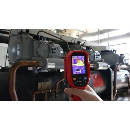 Termokamera meria teplotu chladiaceho zariadenia. Na displeji je zobrazená teplota 48,1°C a -90,6°C. Zariadenie je umiestnené v technickej miestnosti s rozsiahlym potrubím.
