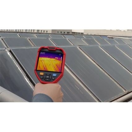Termokamera sníma teplotu solárnych panelov na streche budovy. Displej termokamery zobrazuje infračervený záber s teplotou 24,6°C. Viditeľné sú rady solárnych panelov na plochej streche.