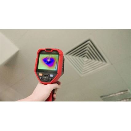 Termokamera sníma teplotu stropného ventilačného otvoru. Ruka drží červenú termokameru s displejom zobrazujúcim teplotné rozloženie. Ventilačný otvor je štvorcový s koncentrickými otvormi.