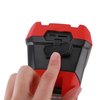 Ruka otvára červeno-čierne zariadenie s USB a microSD konektorom. Zariadenie je kompaktné, hranaté a drží sa v ruke.