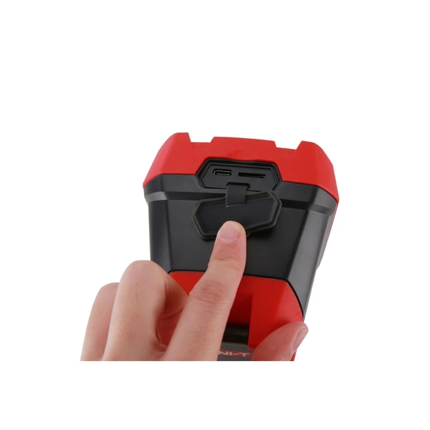 Ruka otvára červeno-čierne zariadenie s USB a microSD konektorom. Zariadenie je kompaktné, hranaté a drží sa v ruke.