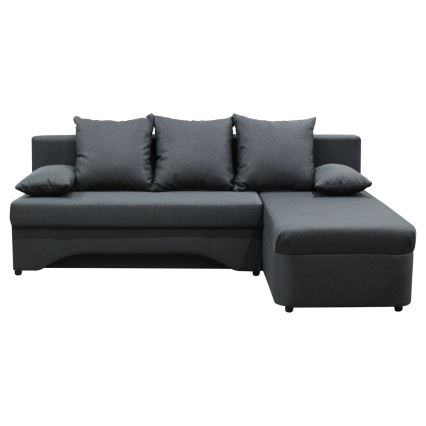 Rohová sedačka s tromi vankúšmi stojí v modernom interiéri. Sedačka je tmavosivá, s ľavostranným nástavcom. Nachádza sa v miestnosti s veľkým oknom a svetlou podlahou.