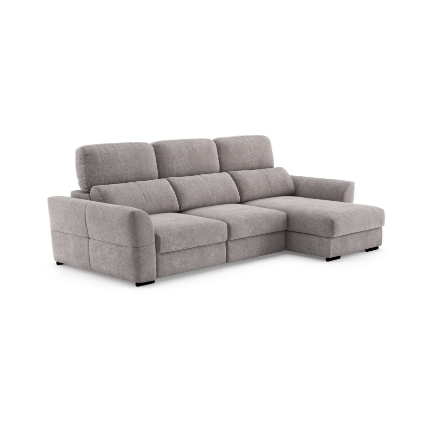 Rohová sedačka s rozkladacím úložným priestorom je umiestnená v obývacej izbe. Na stene visí obraz s Johnom Lennonom a text „An evening with the music of John Lennon“. Sedačka stojí na svetlom koberci pred konferenčným stolíkom.