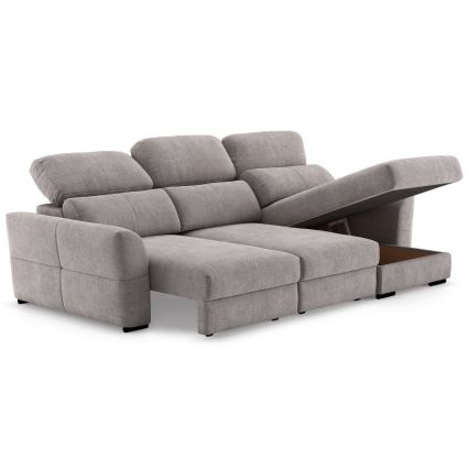 Rohová sedačka s otvoreným úložným priestorom v ľavej časti. Sedačka je svetlosivá, látková, s viacerými vankúšmi. Nachádza sa na bielom pozadí.