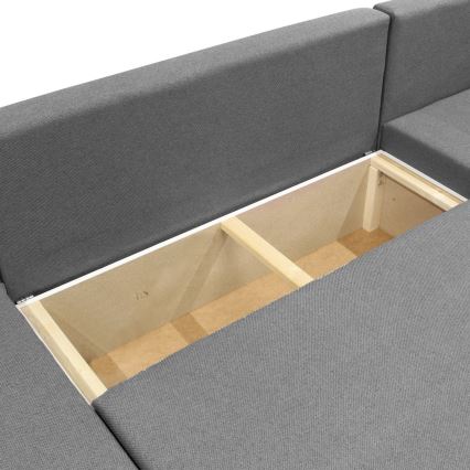 Rohová sedačka s tromi operadlami a jedným vankúšikom je umiestnená na bielom pozadí. Sedačka je sivá a vyzerá byť čalúnená látkou.