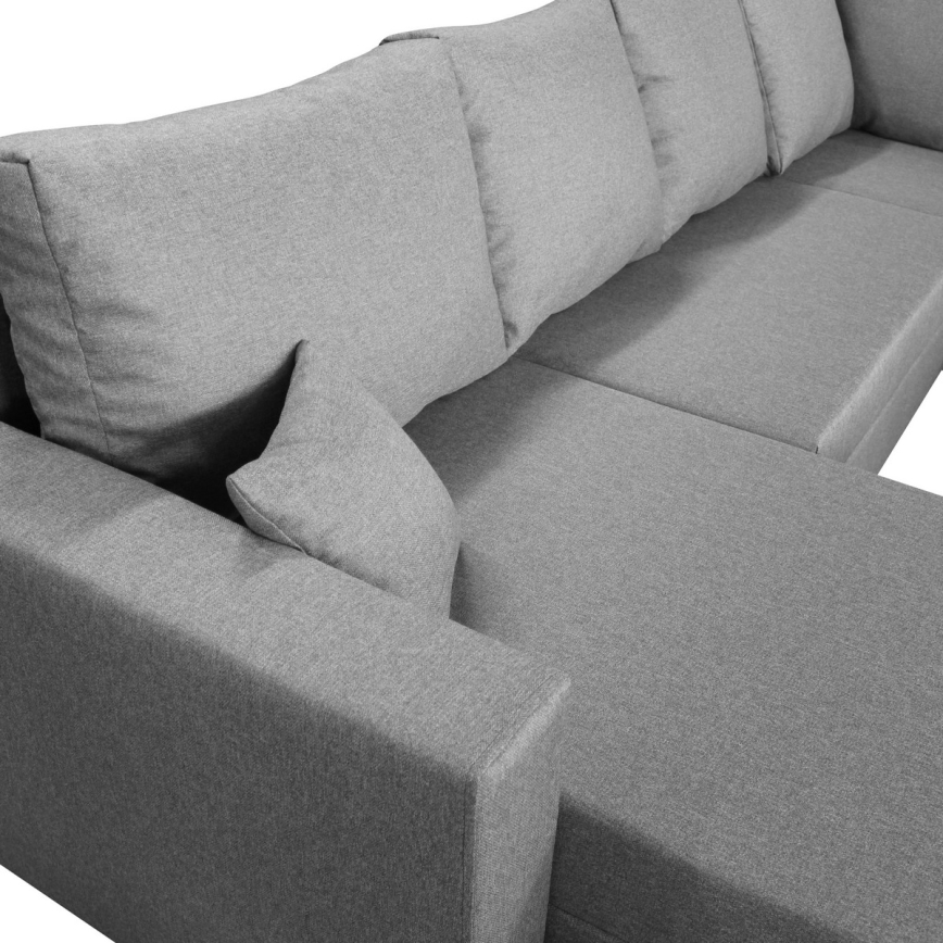 Detail sivého čalúnenia rohovej opierky nábytku. Textúra je tkaná, s viditeľnými vláknami. Opierka je hranatá a pevná.