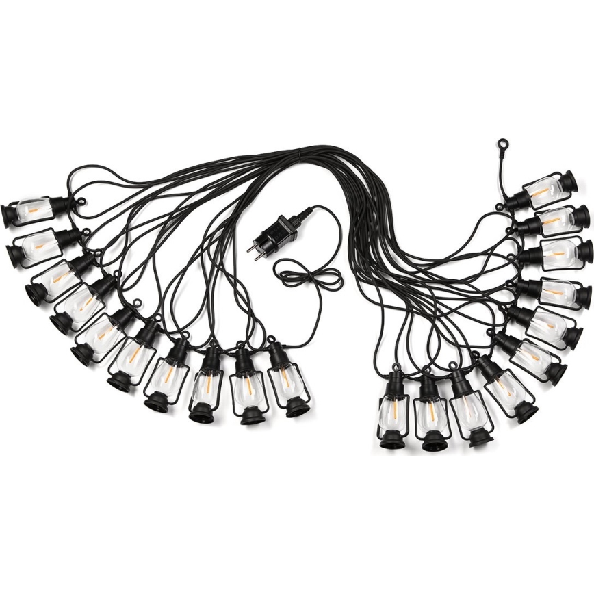 Svetelný reťaz s pätnástimi malými čiernymi lampášikmi s teplým svetlom je zapojený do elektrickej siete. Lampáše visia na čiernom kábli na bielom pozadí.