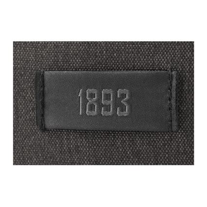 Štítkom s číslom 1893 je prišitý na tmavosivú textíliu.